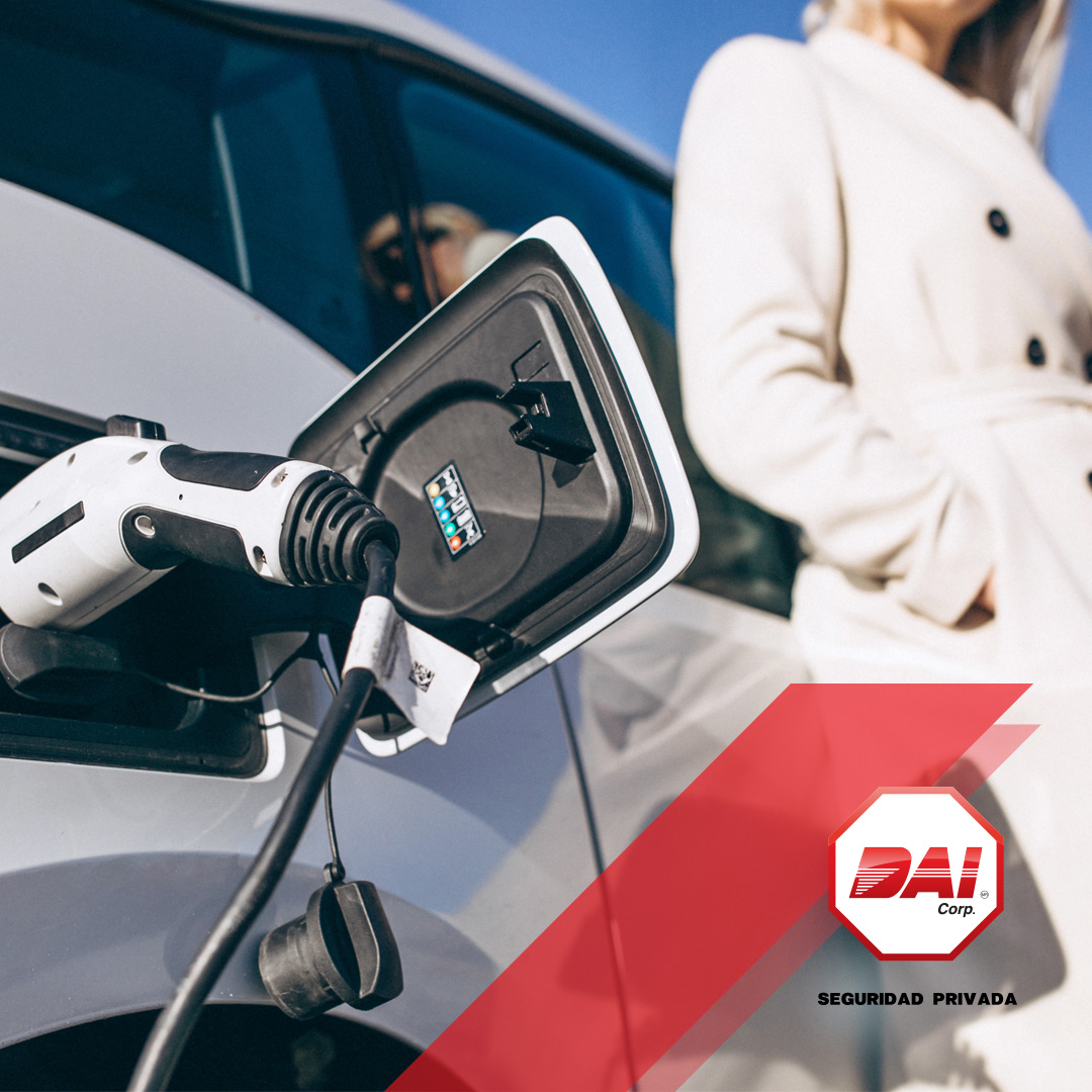 Auto eléctrico conectado a su cargador con una mujer de pie junto a él