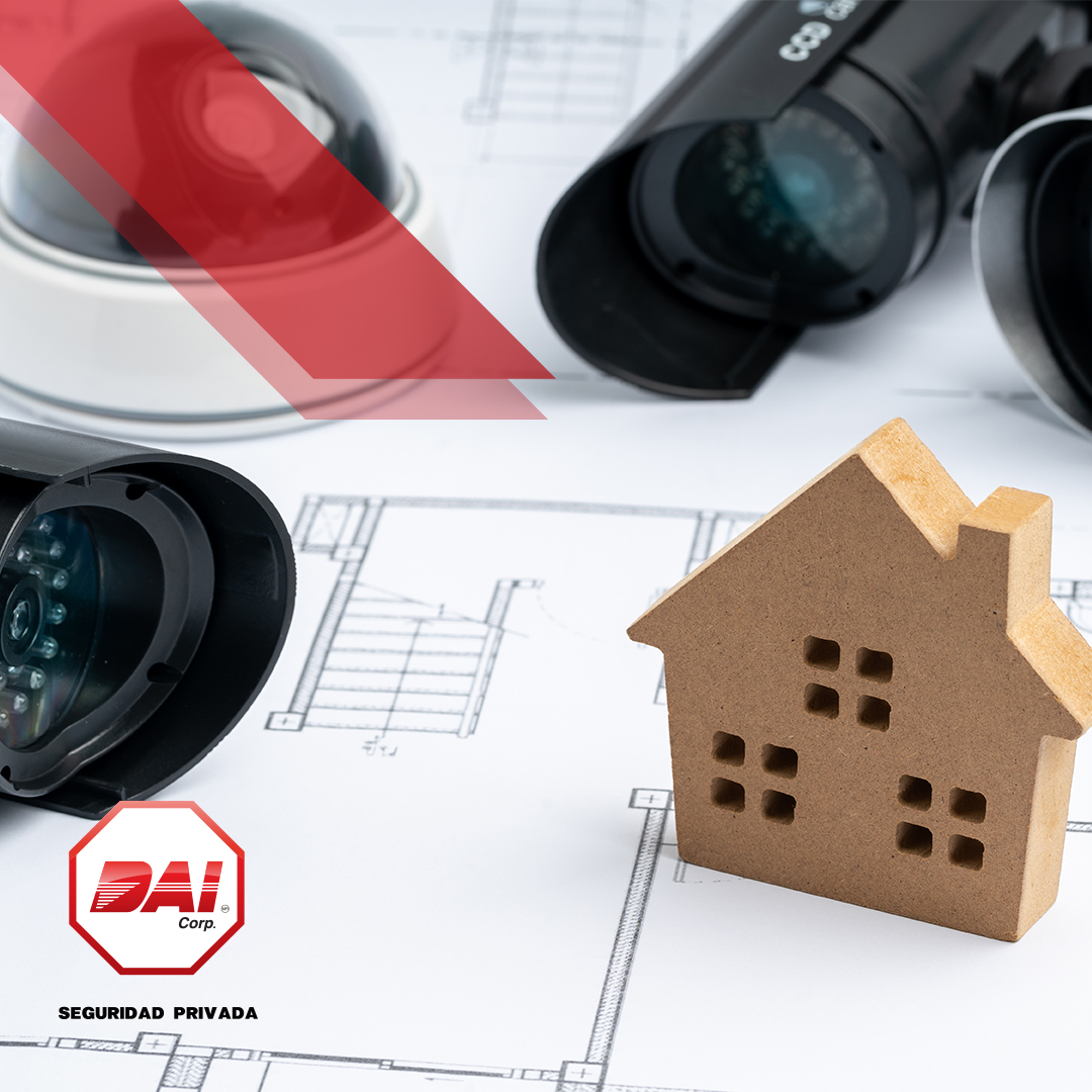 Cámaras de seguridad sobre un plano arquitectónico junto a una casa de madera